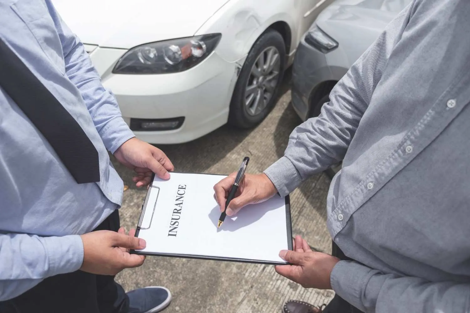 Driver checking auto insurance details beside a parked car